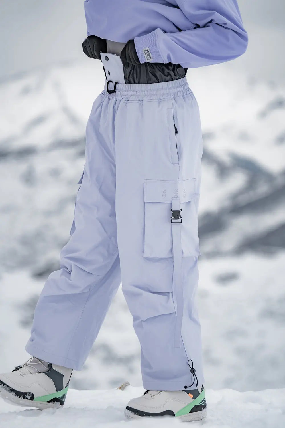Light purple loose winter outdoor ski cargo snow pants with multiple pockets and adjustable drawstrings.