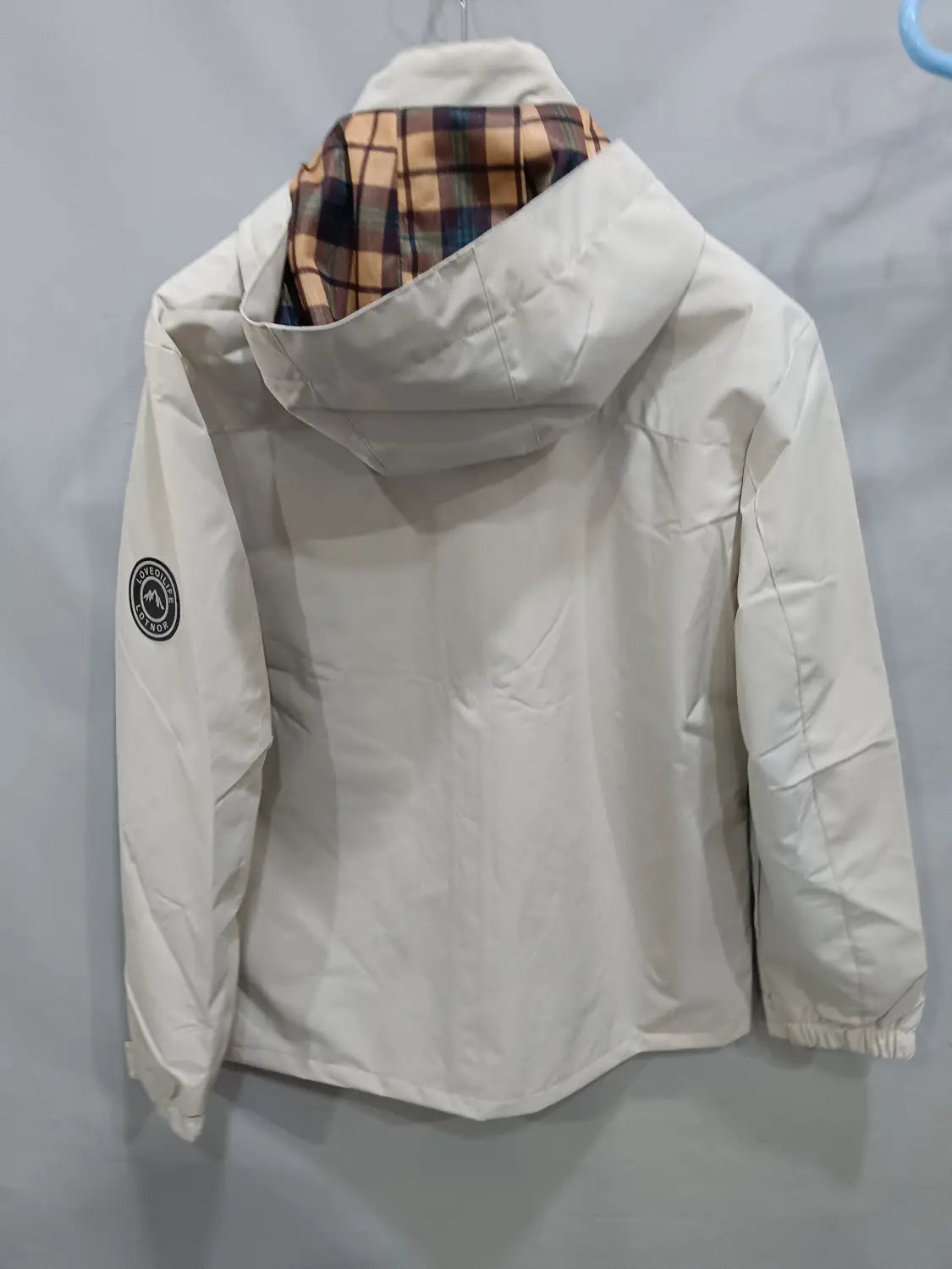 Men winter hooded parka coat in off-white with a plaid-lined interior and a circular logo patch on the left sleeve.