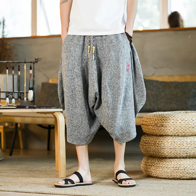 Herren-Shorts aus grauem bedrucktem Baumwollstoff im Lantern-Harem-Look mit weitem Bein mit Kordelzug-Taille und dezenter bestickter Detailausführung.