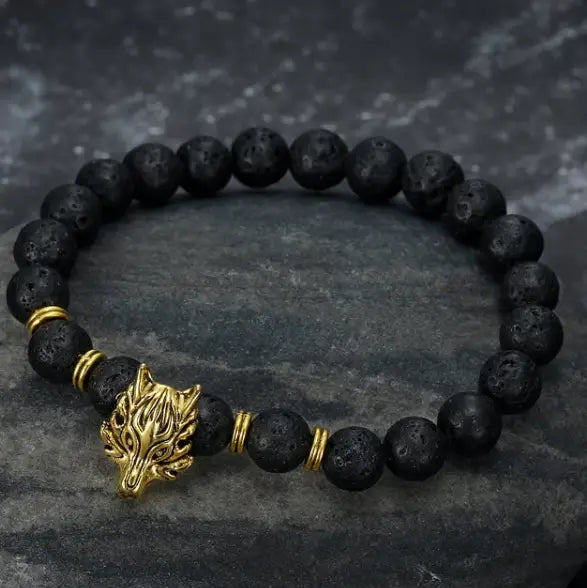 Black lava stone bracelet featuring a gold wolf head charm and brass spacer beads in the asgard wolf head lava stone bracelet design.