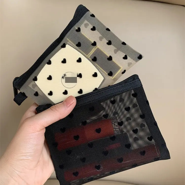 Eine schwarze Mesh-Kosmetiktasche mit schwarzem Herz-Punkte-Muster und Reißverschluss.
