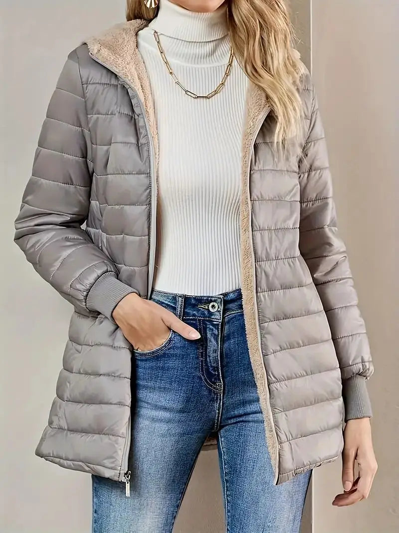 Doudoune matelassée grise pour femme avec une capuche en fourrure polaire beige duveteuse et un matériau chaud et isolant.