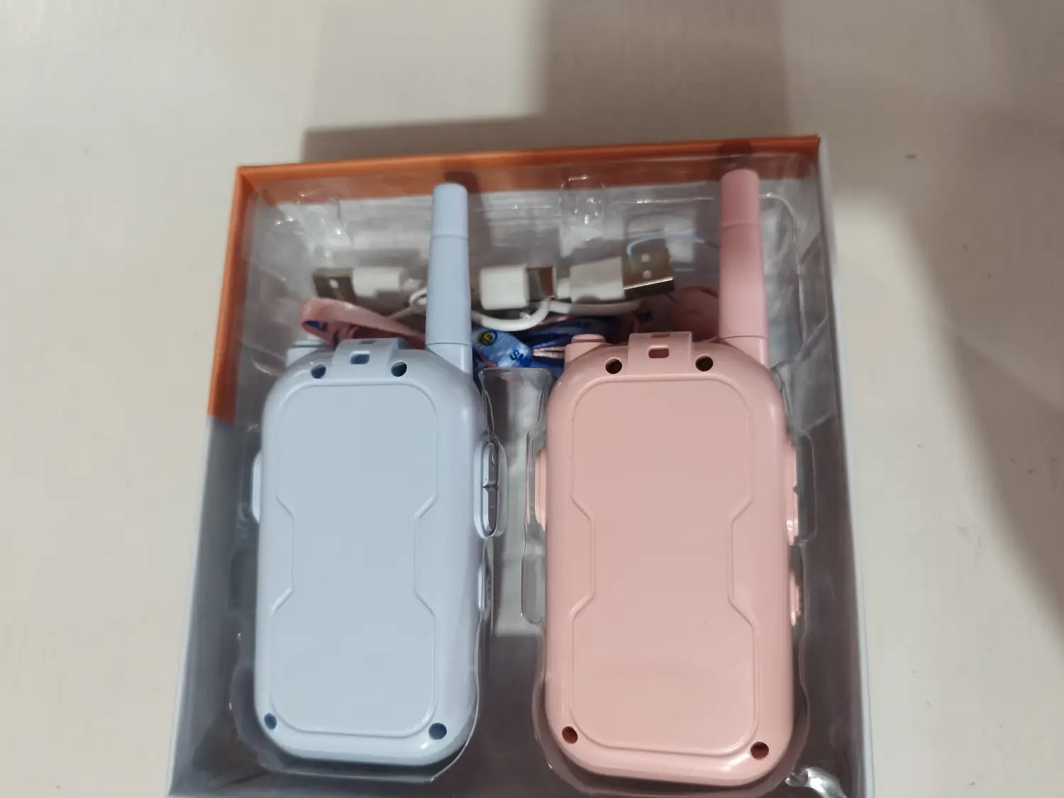 A pair of kids video walkie talkies 2 pack in pastel blue and pink with matching antennas and sleek plastic casing featuring rechargeable intercom functionality.