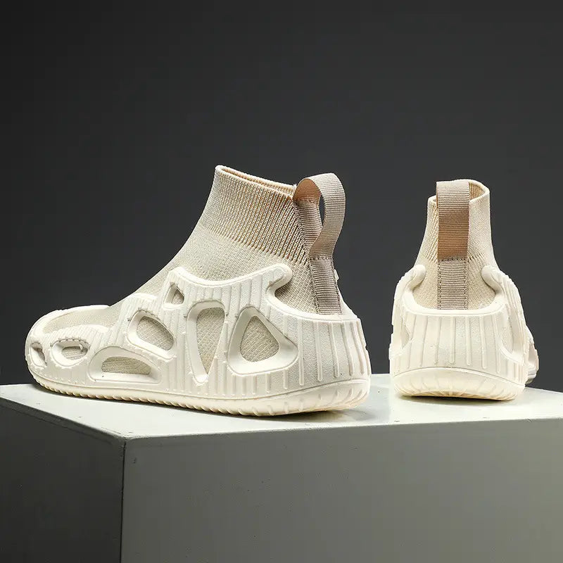 Cremefarbene Strick-Sockensneaker mit geformter, perforierter Gummisohle und beigen Stoff-Zuglaschen für den lässigen, geschlechtsneutralen Einsatz.