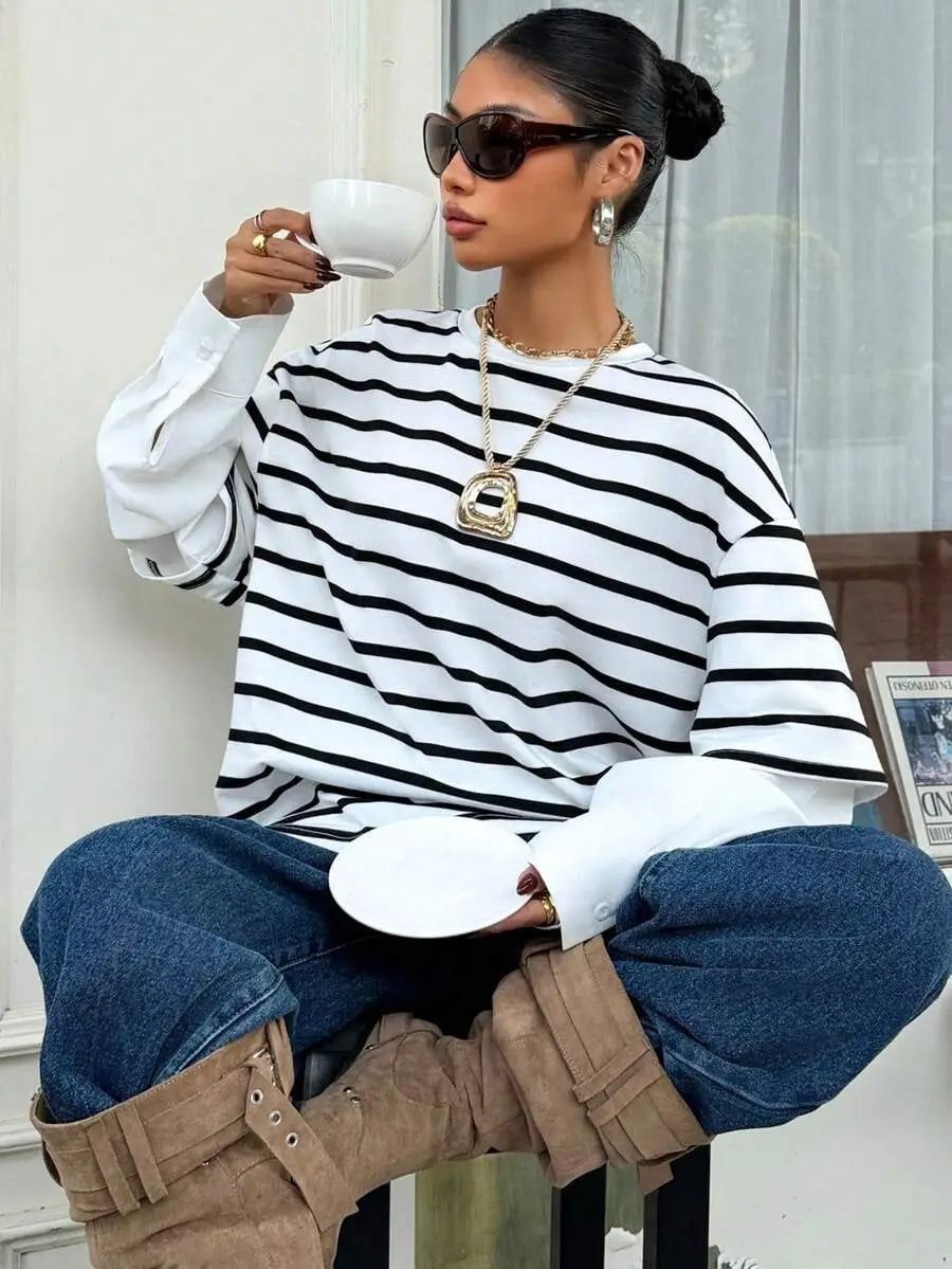 Una mujer que lleva una sudadera oversize con rayas negro y blanco tipo conjunto falso de dos piezas con diseño de top de manga larga.