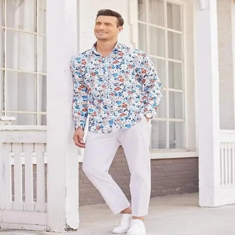 Ein Mann, der ein weißes Hemd mit Knopfleiste und einem farbenfrohen floralen Muster in Blau, Rot und Orange trägt, kombiniert mit Herren-Cotton-Linen-Freizeit-Hosen mit hohem Stretch.
