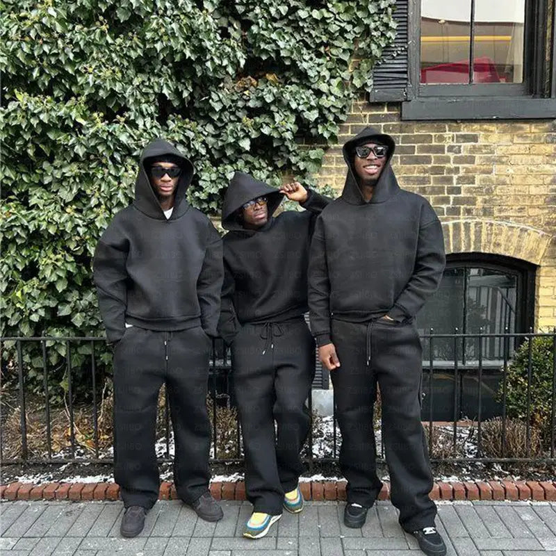 Trois hommes portant des sweats à capuche oversize unisexes assortis et des joggings noirs assortis, en un matériau confortable, idéal pour les tenues décontractées.