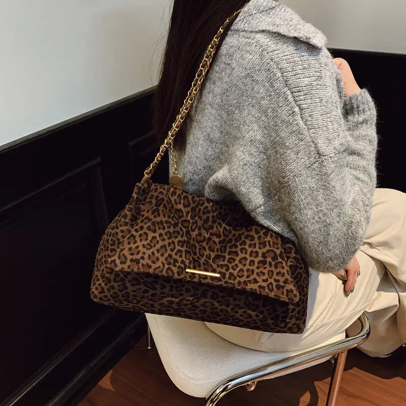 Brown leopard-print crossbody bag featuring a gold chain strap and a minimalist metallic clasp.