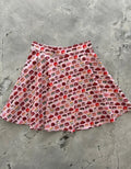 Pink pleated skater skirt featuring a playful illustrated cake print in red brown and beige tones