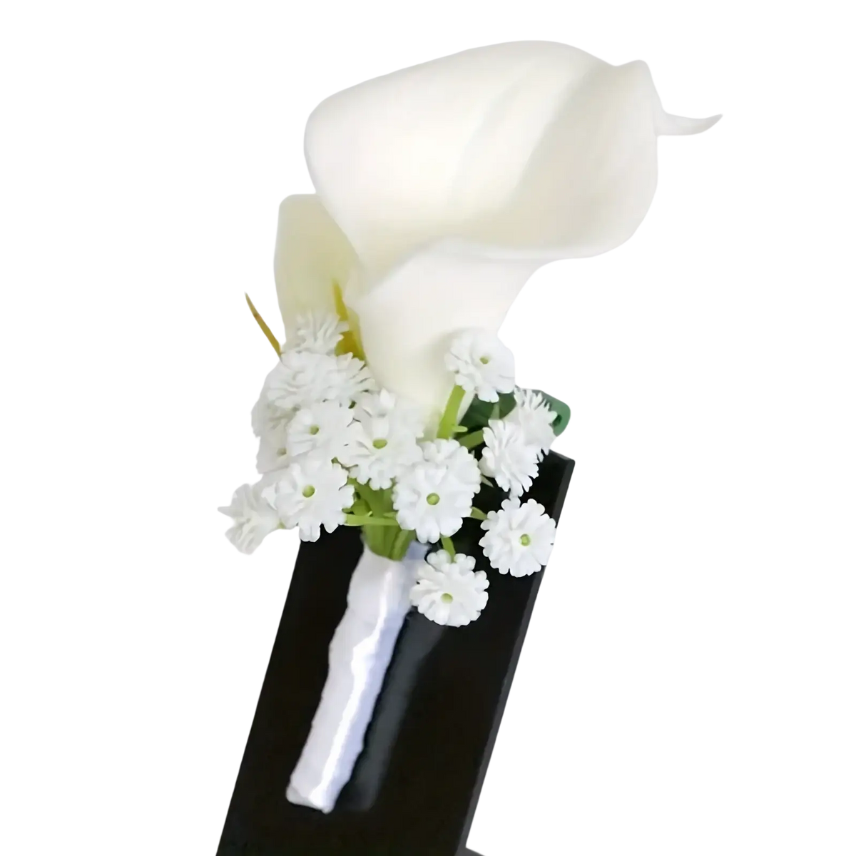 Elegant white calla lily wedding boutonniere accented with baby’s breath displayed on a sleek black stand
