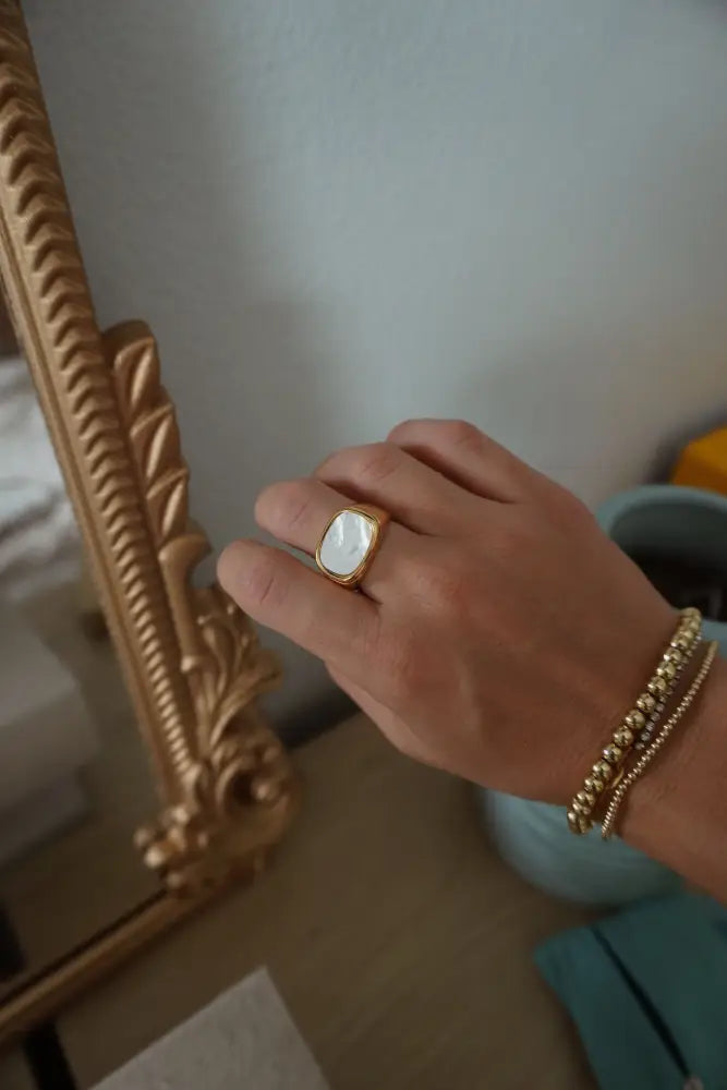 Calypso gold signet ring with a rectangular off-white mother of pearl stone set in a simple gold-toned band