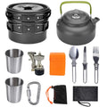Black aluminum camping cookware set with green handle kettle and stainless steel utensils for outdoor cooking