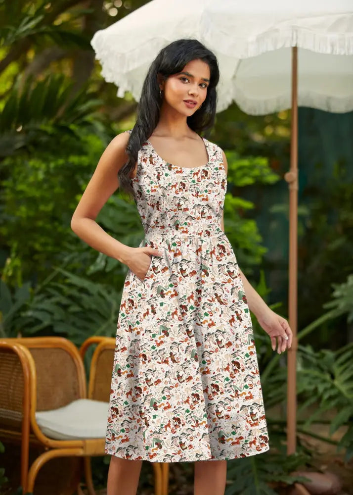 A woman wears a sleeveless campsite print vintage fit and flare cotton dress with colorful cartoon animals