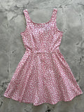 A pink sleeveless candy cane stripe a-line skater dress with a flared skirt and pockets featuring a red candy cane pattern