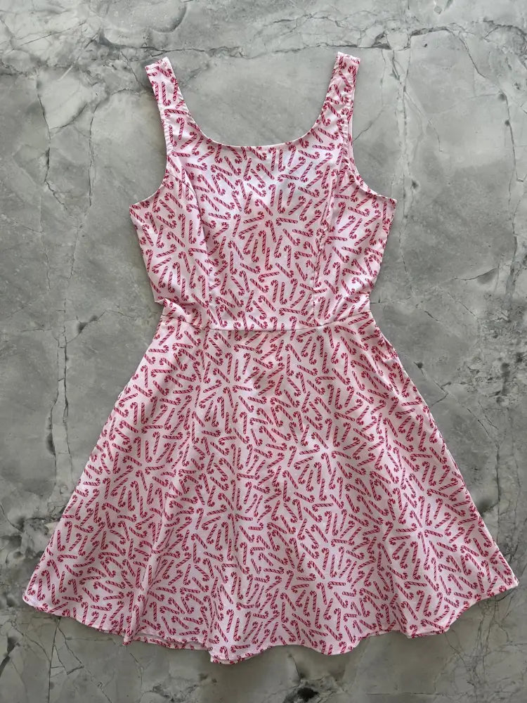 A pink sleeveless candy cane stripe a-line skater dress with a flared skirt and pockets featuring a red candy cane pattern