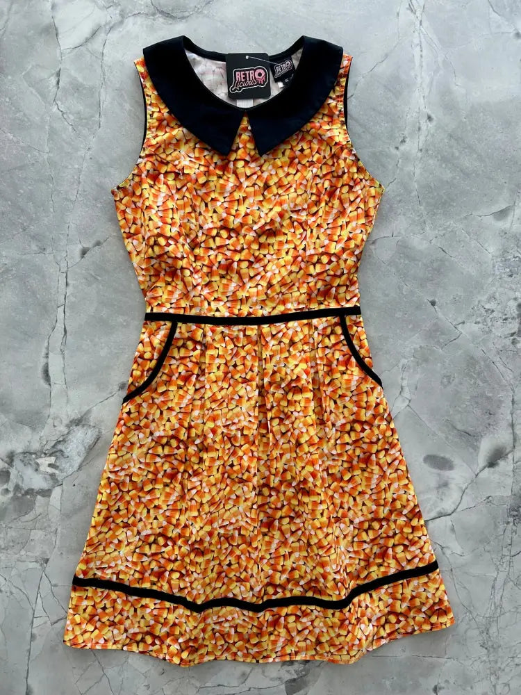 A sleeveless retro candy corn cotton a-line dress with a black peter pan collar and matching trim