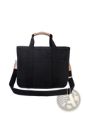 Black canvas messenger bag with tan leather handles and shoulder strap accents for mother and baby travel tote