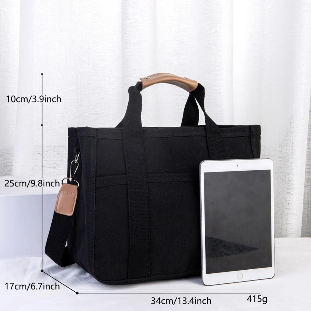 Black canvas messenger bag with tan leather handles and detachable strap for mother and baby travel tote use