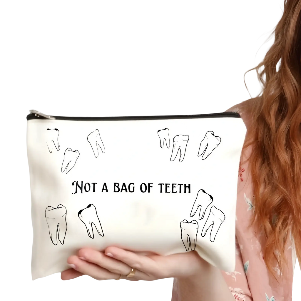 White canvas makeup bag with black tooth illustrations and text not a bag of teeth for travel storage