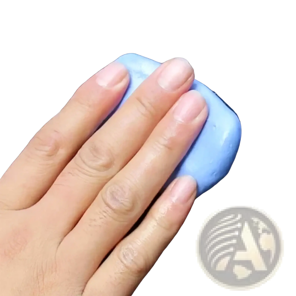 A light blue rectangular car cleaning clay bar with a smooth surface held against a dark wet background
