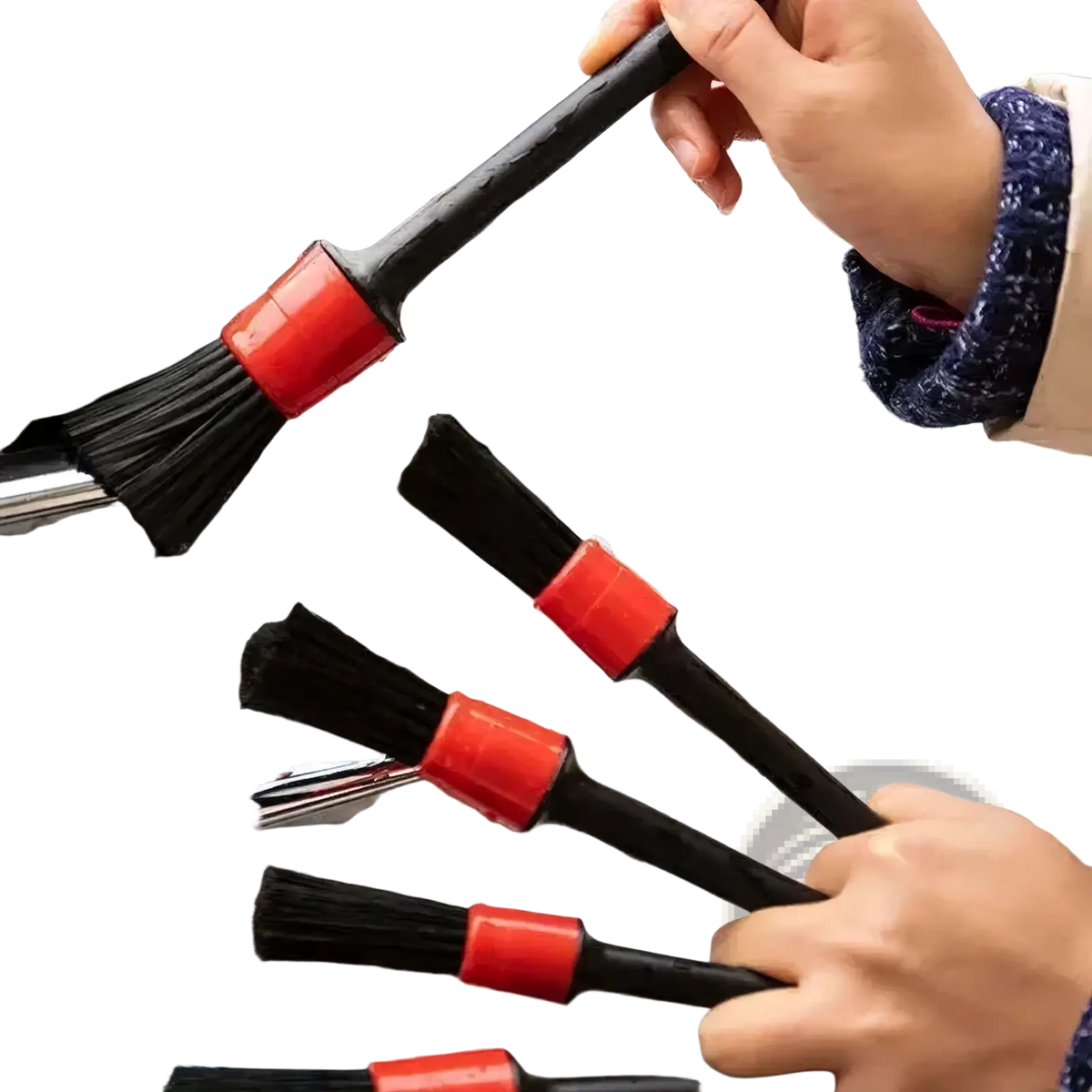 Black car detailing brushes with red plastic handles and nylon bristles scrubbing a soapy chrome grille