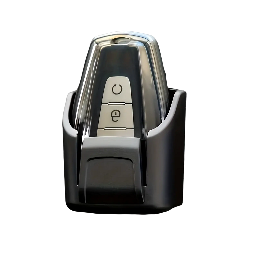 A sleek chrome car key fob with two buttons secure in a black plastic car key organizer dashboard storage box