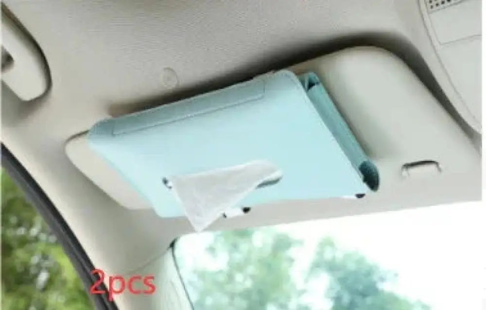 Light blue leather car sun visor tissue box holder with a white tissue partially pulled out for convenient use