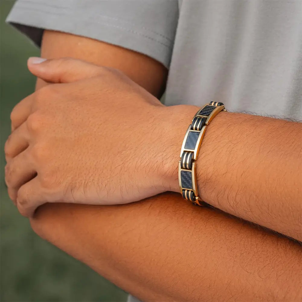 Men’s gold titanium magnetic bracelet featuring alternating dark blue carbon fiber inlays and polished metal links