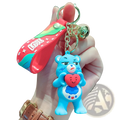 A blue silicone Care Bears keychain with a red heart attached to a rainbow-colored strap and chain backpack pendant