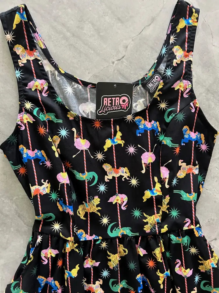 A black sleeveless cotton fit and flare mini dress with a vibrant retro carousel print on shiny fabric
