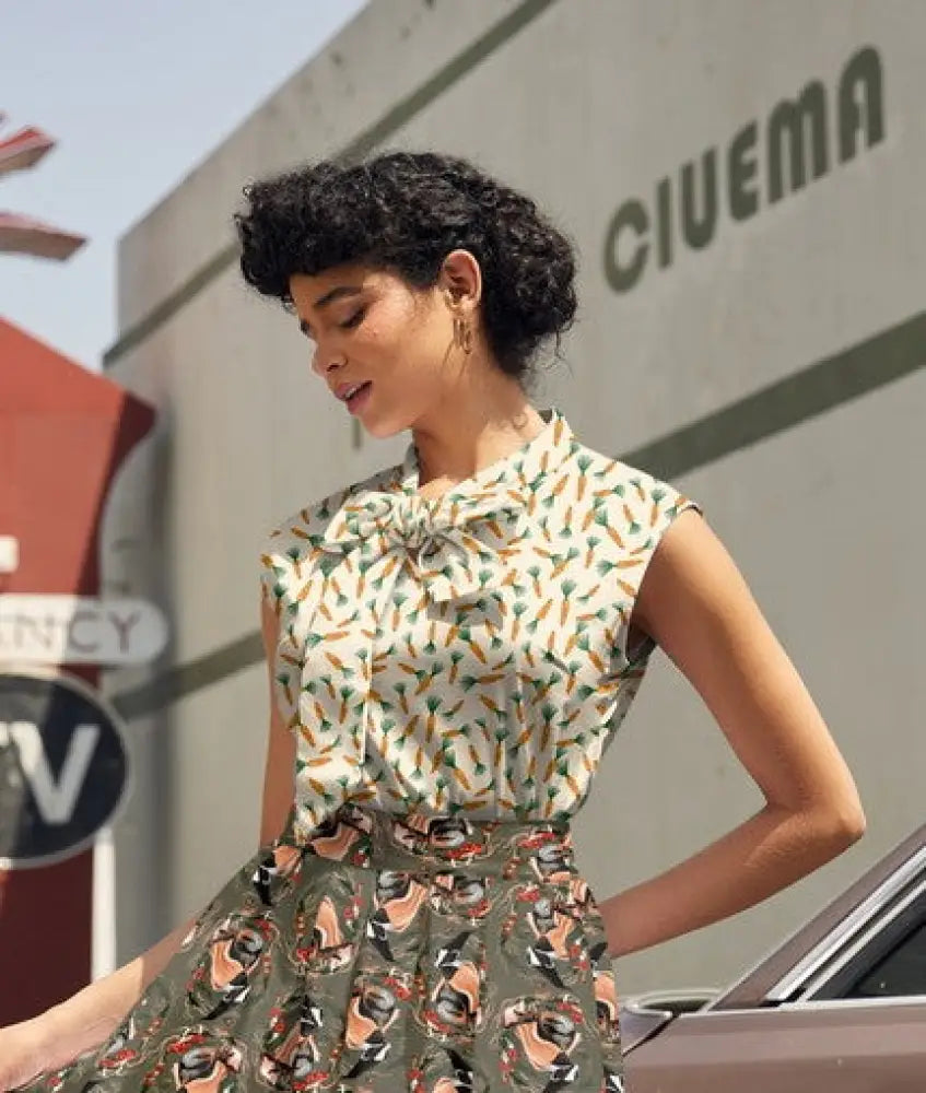 A woman wears a vintage 1950s style sleeveless blouse and matching skirt with orange and green carrot print