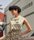 A woman wears a vintage 1950s style sleeveless blouse and matching skirt with orange and green carrot print