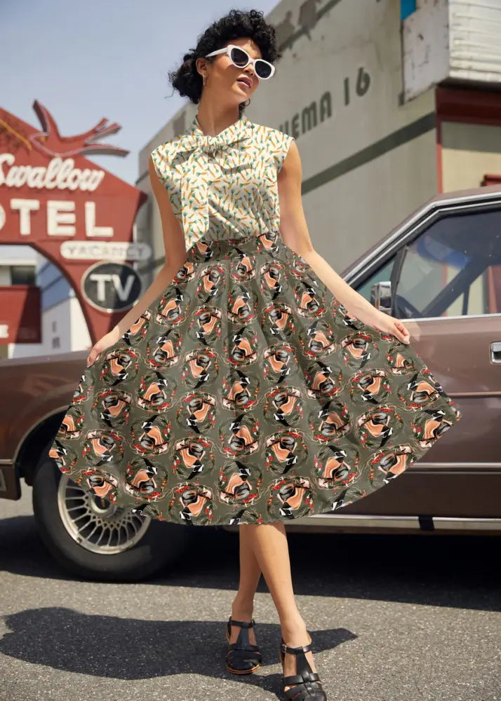 A vintage 1950s style olive green skirt with a repeating circular pattern featuring stylized peach black and red faces