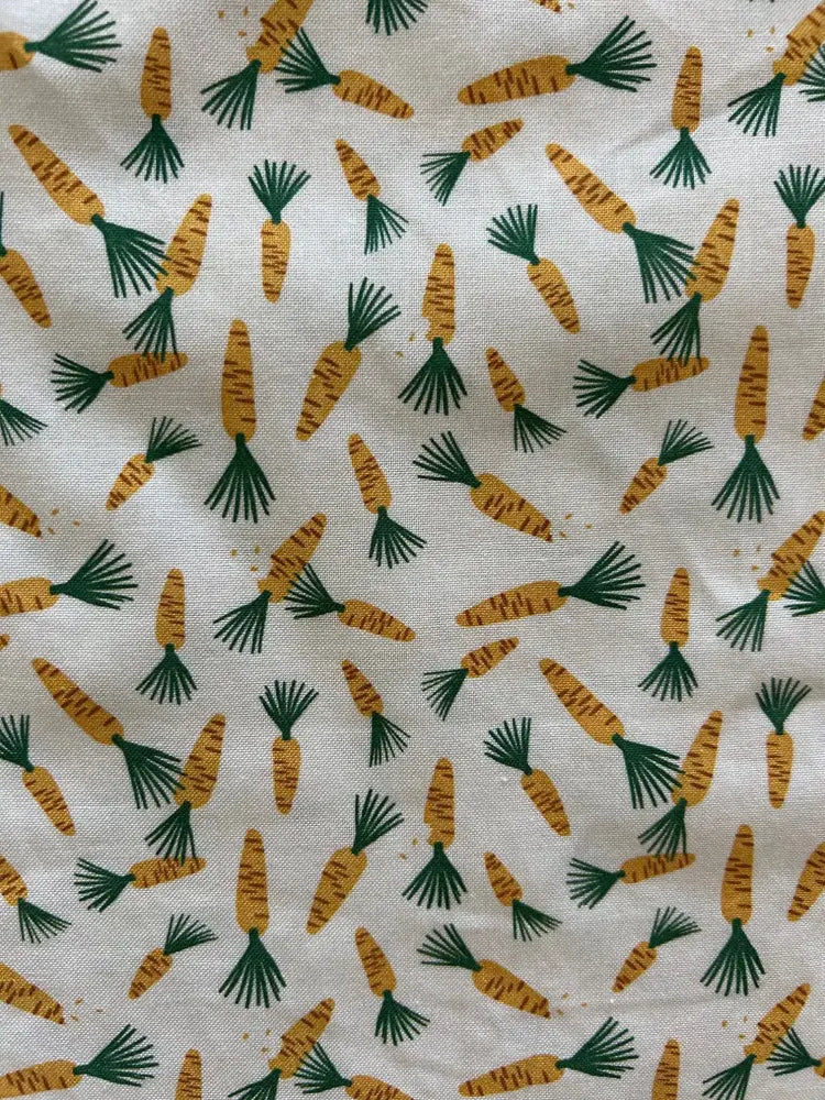 White fabric with a repeating orange carrot print featuring green leafy tops for vintage 1950s style bow top