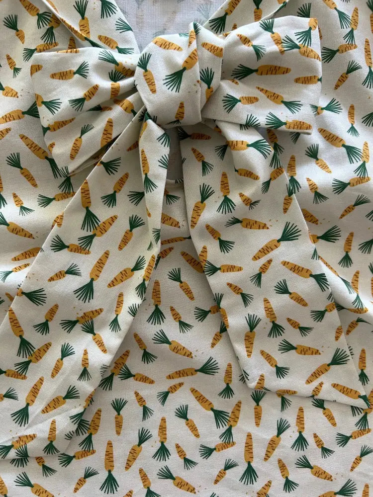 Vintage 1950s style white fabric bow top with repeating orange carrot pattern and green tops