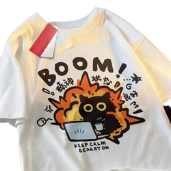 White cotton oversized t-shirt featuring a cartoon black cat with orange flames and bold brown text boom keep calm carry on