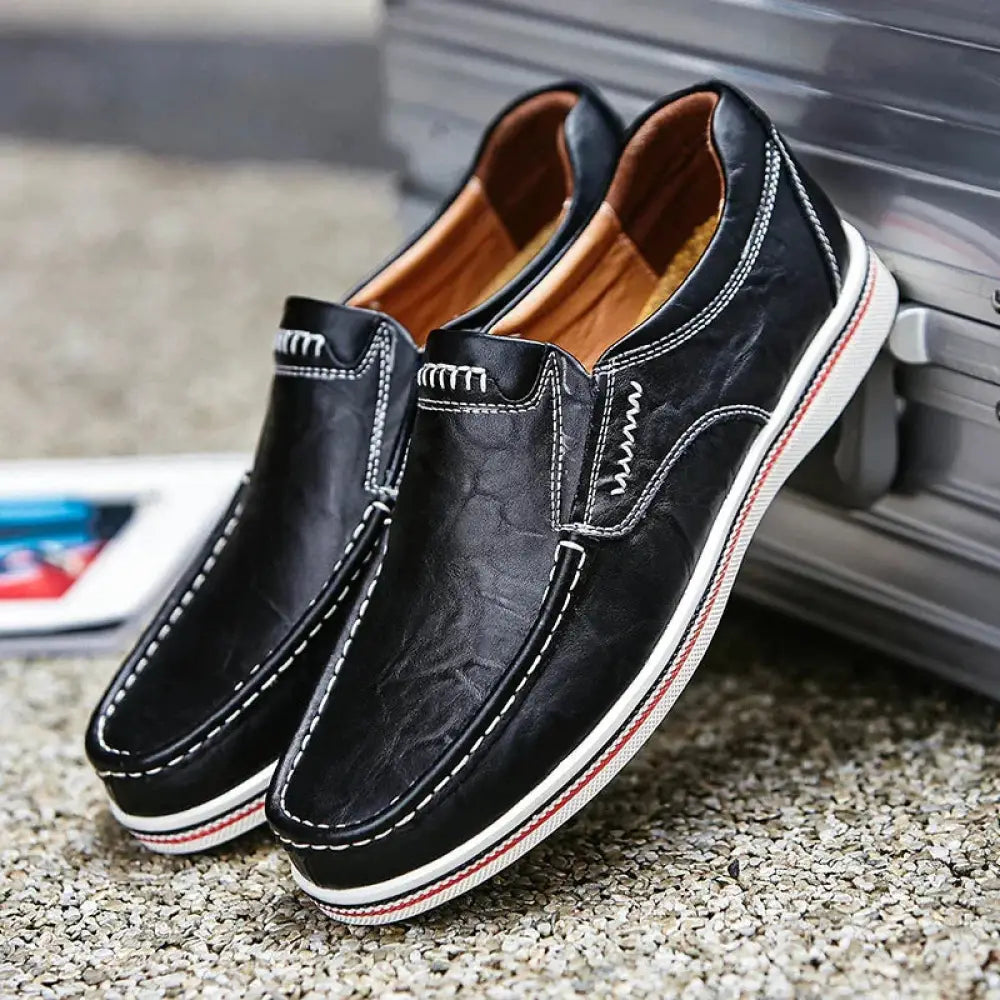 Men’s black British leather slip-on shoes with white stitching and a red and white striped sole
