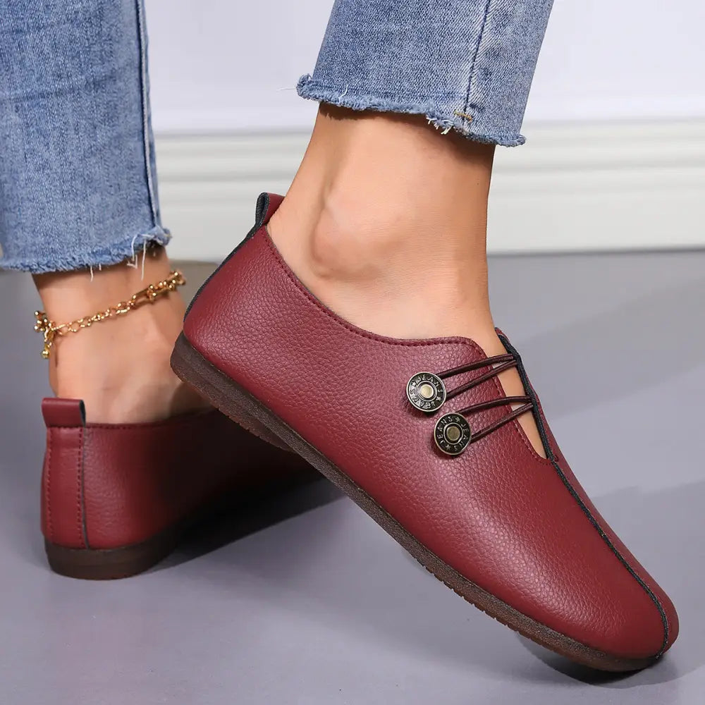 Burgundy leather women’s square toe slip-on loafers with decorative metal buttons and a flat sole