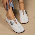 Women’s square toe white leather loafers with decorative silver toned button closures and a flat sole