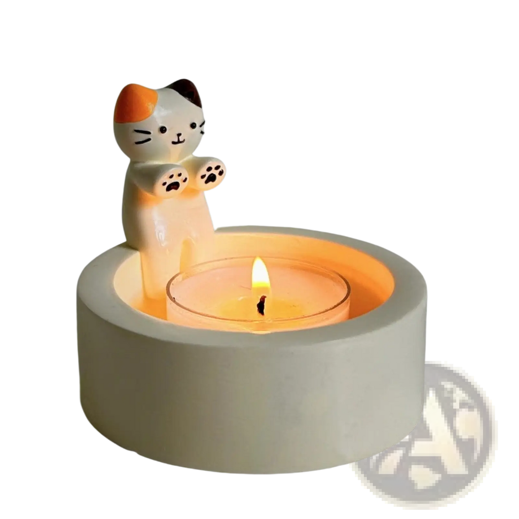 Cute white ceramic cat candlestick holder with orange and black accents holding a lit tea light candle