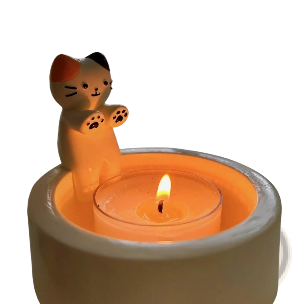Cute ceramic cat candlestick holder with orange and black accents holding a lit tealight candle for home decor