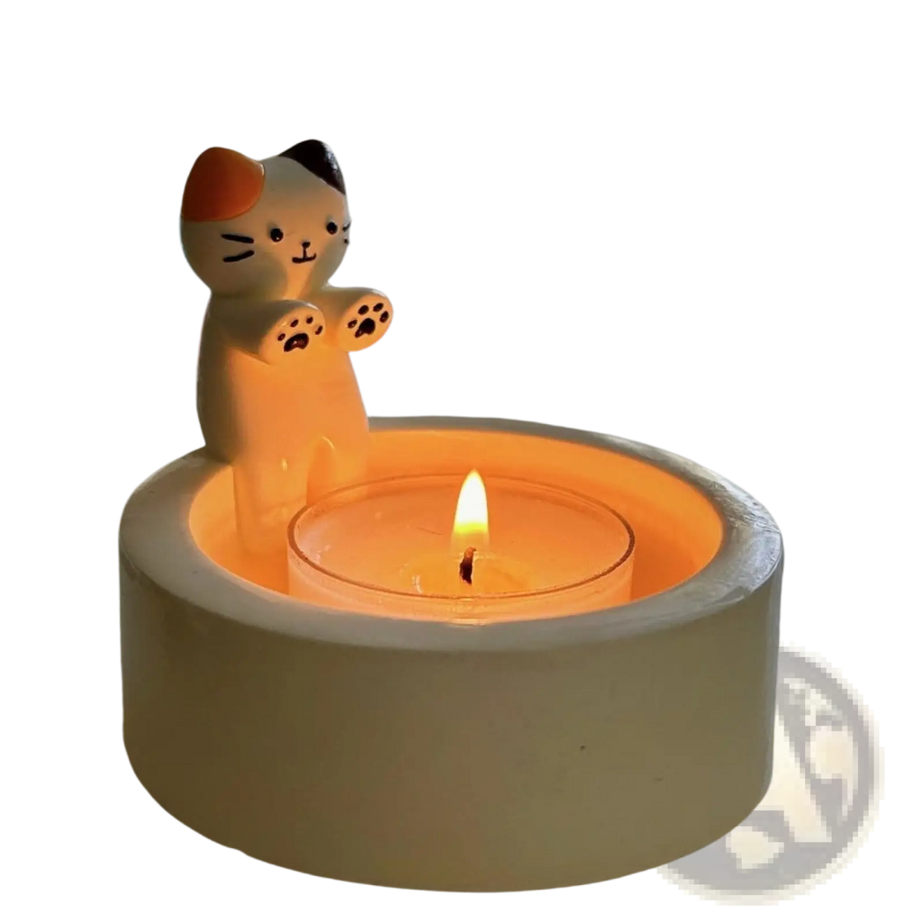 Cute calico cat ceramic candlestick holder with orange black and white markings holding a lit tealight candle