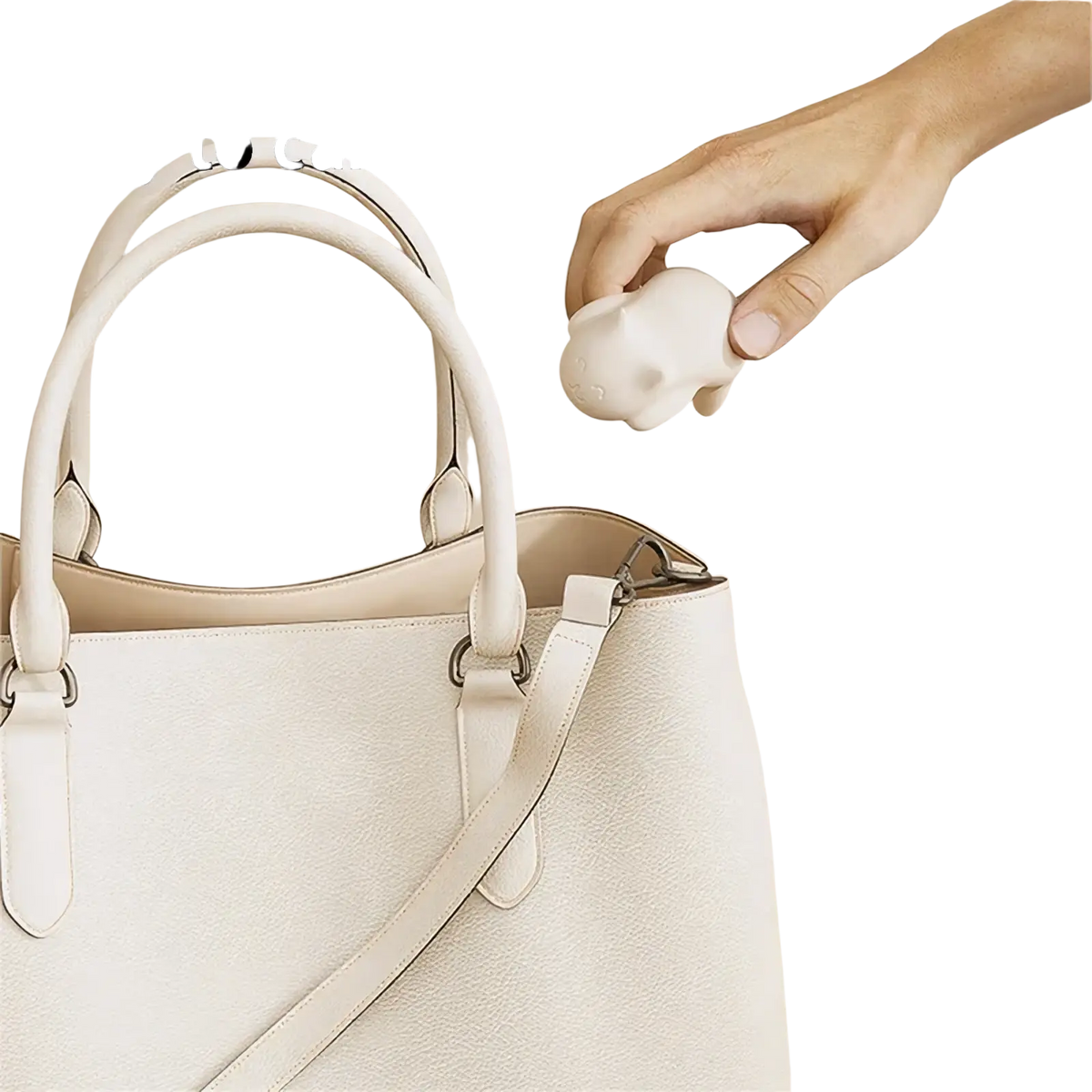 A white compact silicone elephant-shaped cat desk hook portable organizer held above a beige handbag