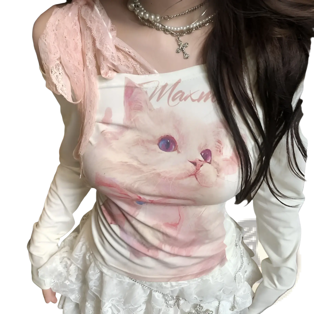 White long-sleeved top with pink cat graphic purple eyes and maxm text layered under sheer lace halter overlay