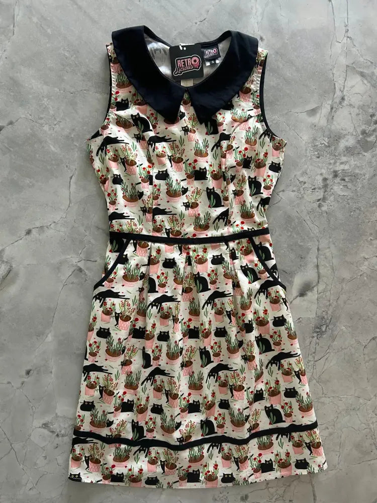 A sleeveless white cotton dress with black velvet peter pan collar and playful black cats in pink pots pattern