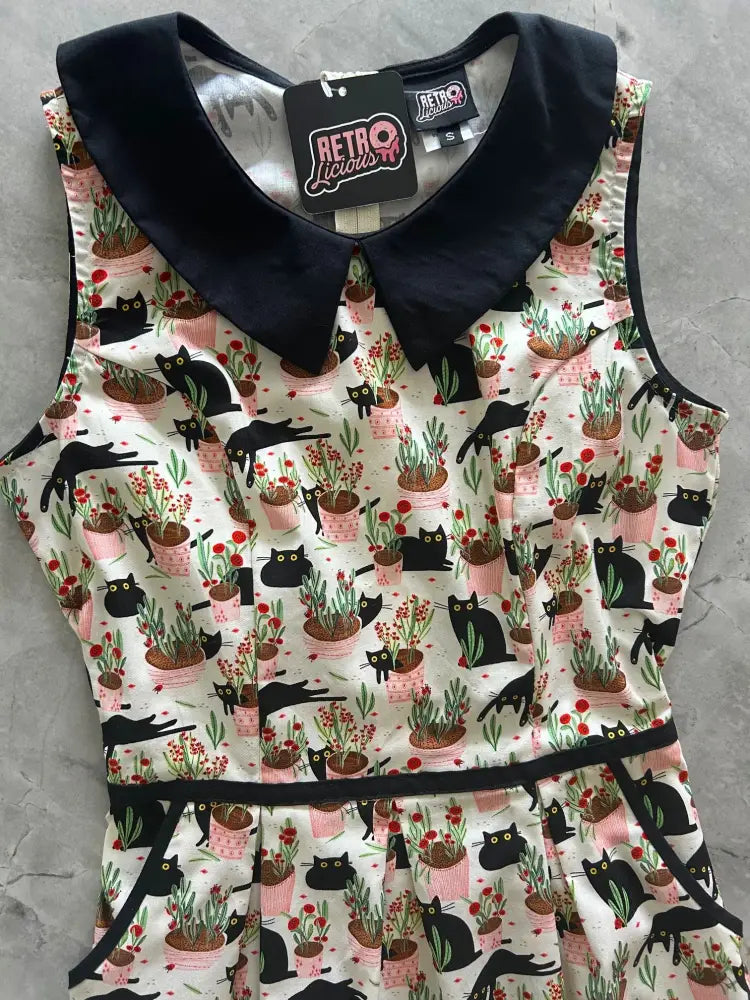 Sleeveless white cotton dress with black velvet Peter Pan collar and belt featuring black cats in pink pots pattern