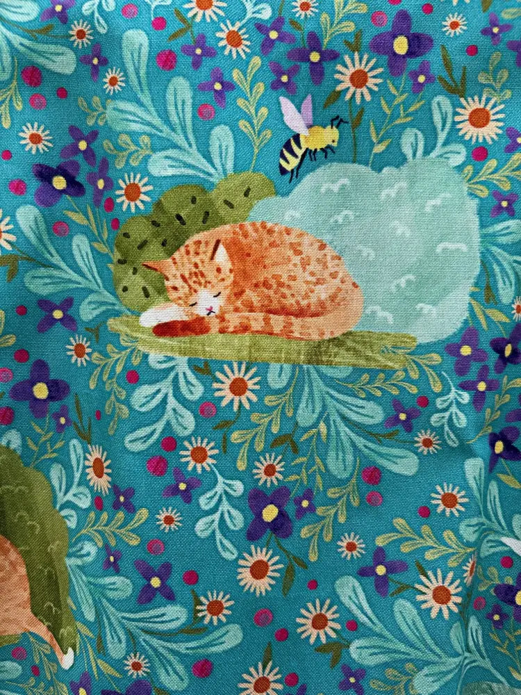 A teal floral cat print sleeveless skater dress with pockets featuring a cozy orange tabby cat on flowers