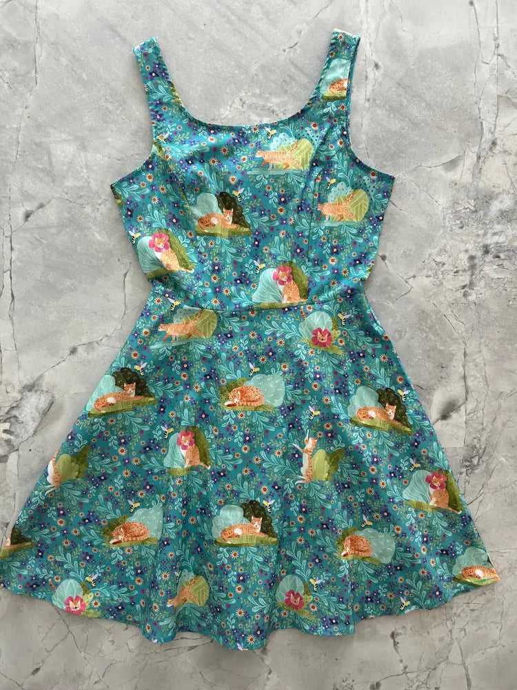 Teal sleeveless skater dress with pockets featuring a playful sleeping fairies and floral print pattern