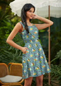 A sleeveless teal skater dress with cartoon snails and green foliage pattern featuring pockets