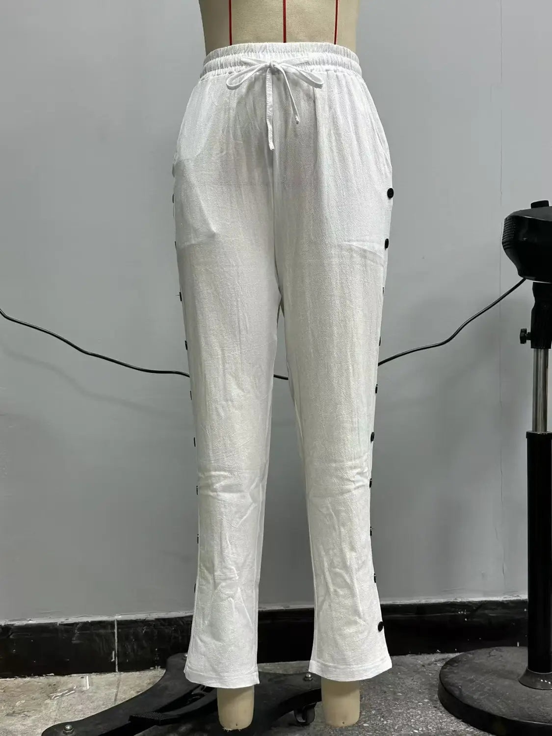 White linen cropped patchwork button casual pants for women featuring black buttons down the sides and a drawstring waist.